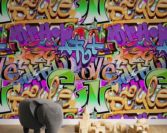 以下が含まれることがあります： 様々なフォントと色で「Hip Hop Art Love」という言葉が描かれた、カラフルなグラフィティスタイルの壁画。 象の形をした灰色のオットマンと木製のおもちゃのブロックが壁の前にあります。
