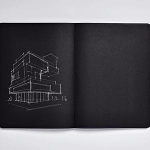 May include: Open black notebook with a white architectural sketch on the left page. The sketch depicts a modern building with geometric shapes and lines. The right page is blank.