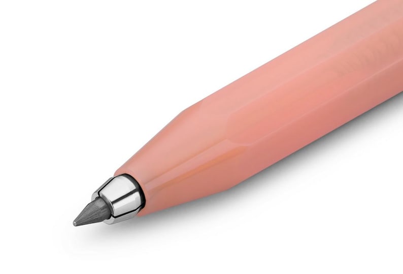 May include: Close-up of a peach-colored mechanical pencil. The pencil has a metallic silver tip and a dark gray lead. The body of the pencil is smooth and angled, with a modern design.