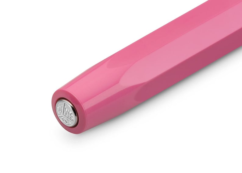 May include: Close-up of a pink fountain pen. The pen has a glossy finish and a geometric design. The end of the pen features a silver emblem. The pen is set against a white background.