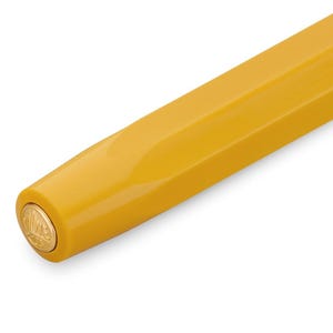 Op de afbeelding: Close-up van het uiteinde van een gele pen met een gouden dop met een logo.