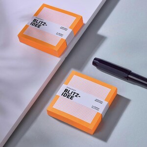 Puede incluir: Dos pilas cuadradas de notas adhesivas de color naranja neón con una banda de papel blanca que muestra el texto BLITZ-IDEE, FOX&POET y 72 x 72 mm. Un bolígrafo negro se encuentra junto a la pila inferior, con 50 hojas cada una.