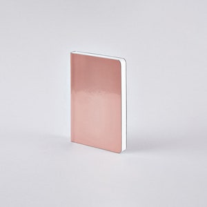 May include: A rose gold notebook with a glossy cover. The notebook is rectangular and stands upright against a white background. The edges of the pages are white.