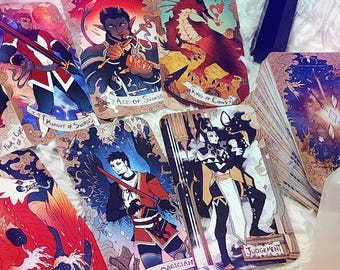 May include: A collection of tarot cards with fantasy illustrations, including the Knight of Swords, Ace of Swords, King of Coins, The Magician, and Judgement. The cards feature detailed artwork with vibrant colors and are arranged on a soft, white surface.