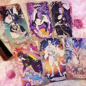 Pu&ograve; includere: Una collezione di carte dei tarocchi con illustrazioni dettagliate. Le carte presentano varie figure e simboli, tra cui un diavolo, un centauro e una figura in bianco. Ogni carta ha un design unico con titoli come "Two of Cups" e "Queen of Swords".