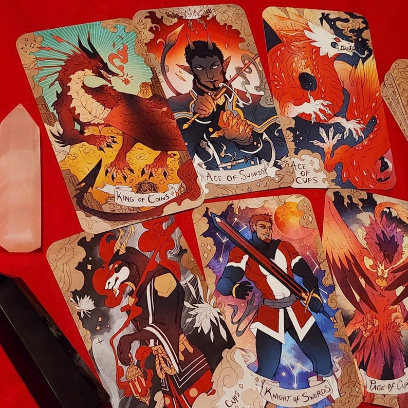 Pu&ograve; includere: Un mazzo di carte dei tarocchi con illustrazioni fantasy. Le carte mostrano immagini di un drago, una figura con le corna e altri personaggi. Le carte hanno titoli come "King of Coins", "Ace of Swords" e "Knight of Swords."