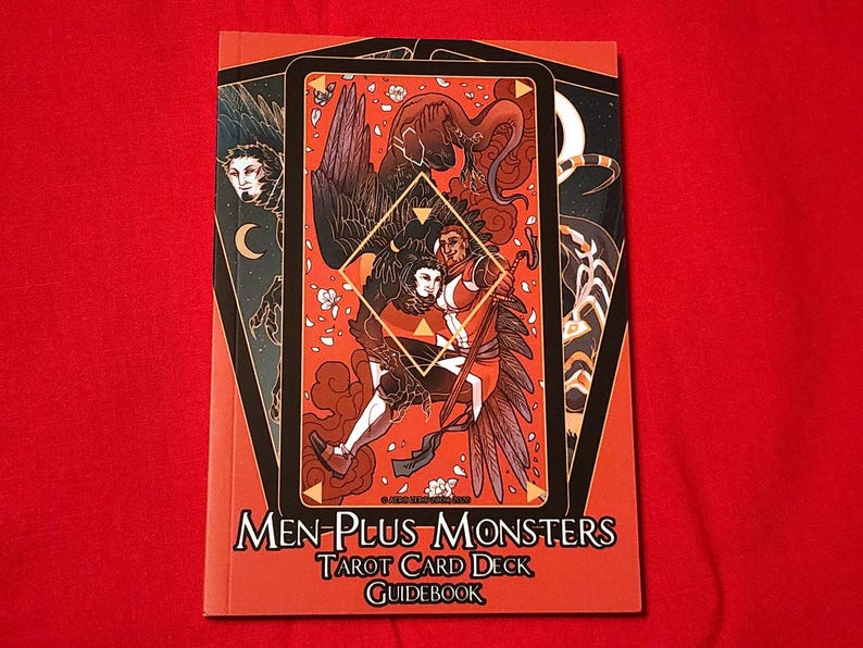 May include: A red guidebook with the title "Men-Plus Monsters Tarot Card Deck Guidebook" and an illustration of two figures with wings on the cover.