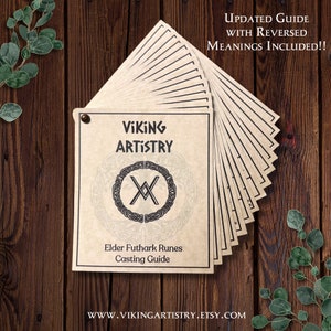 Pode incluir: Um conjunto de guias de lançamento de runas Elder Futhark com o texto "VIKING ARTISTRY" e um emblema circular. Os guias estão sobre uma superfície de madeira com o texto "UPDATED GUIDE WITH REVERSED MEANINGS INCLUDED!!" e o site www.vikingartistry.etsy.com.