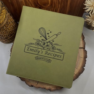 May include: A green leather recipe binder with a floral design, a rolling pin, a whisk, and the text "Emily's Recipes Made With Love".
