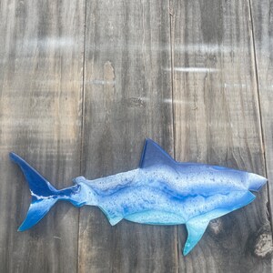 May include: A blue and white resin shark wall decor. The shark is in a side profile with its mouth open. The shark is painted with a blue and white marbled effect.