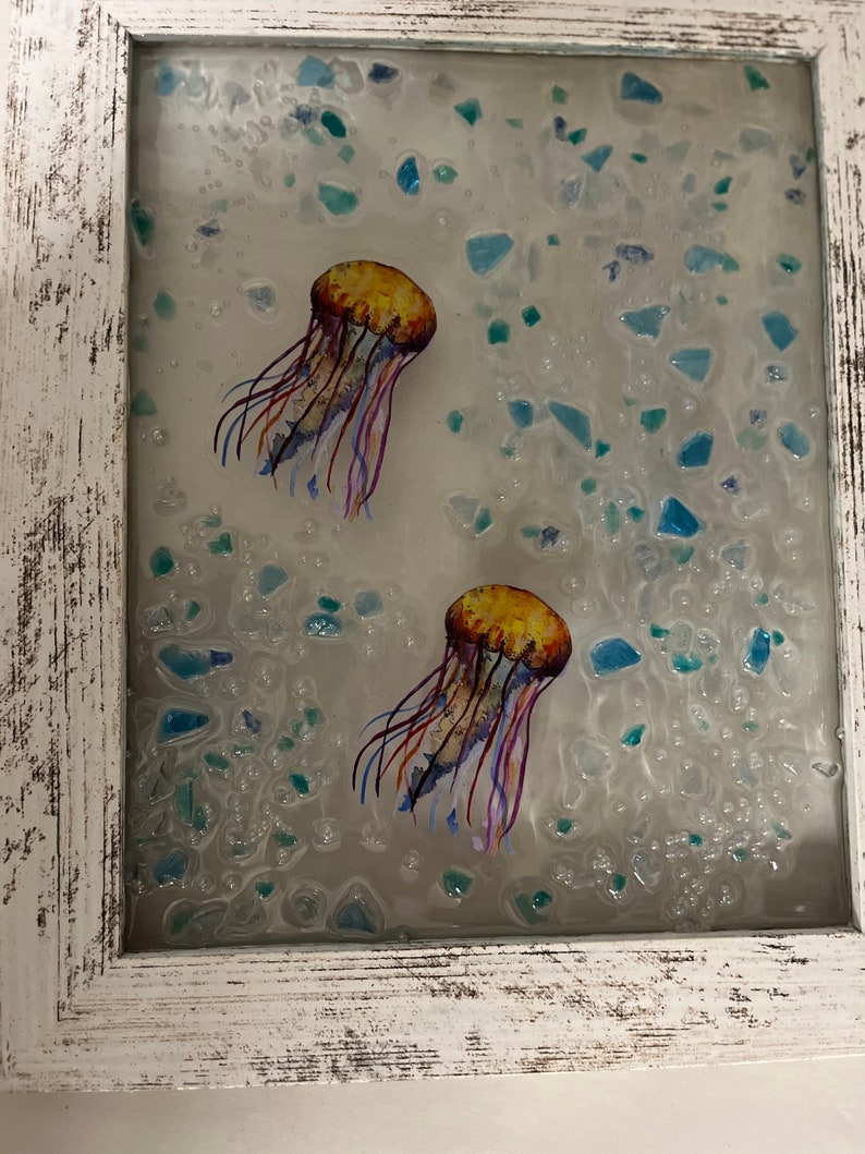 May include: A framed artwork featuring two yellow jellyfish with purple tentacles against a white background with blue and green glass pieces.