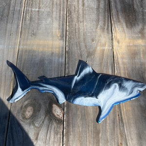 May include: A black and white shark wall decor with blue accents. The shark is made of metal and has a marbled finish.