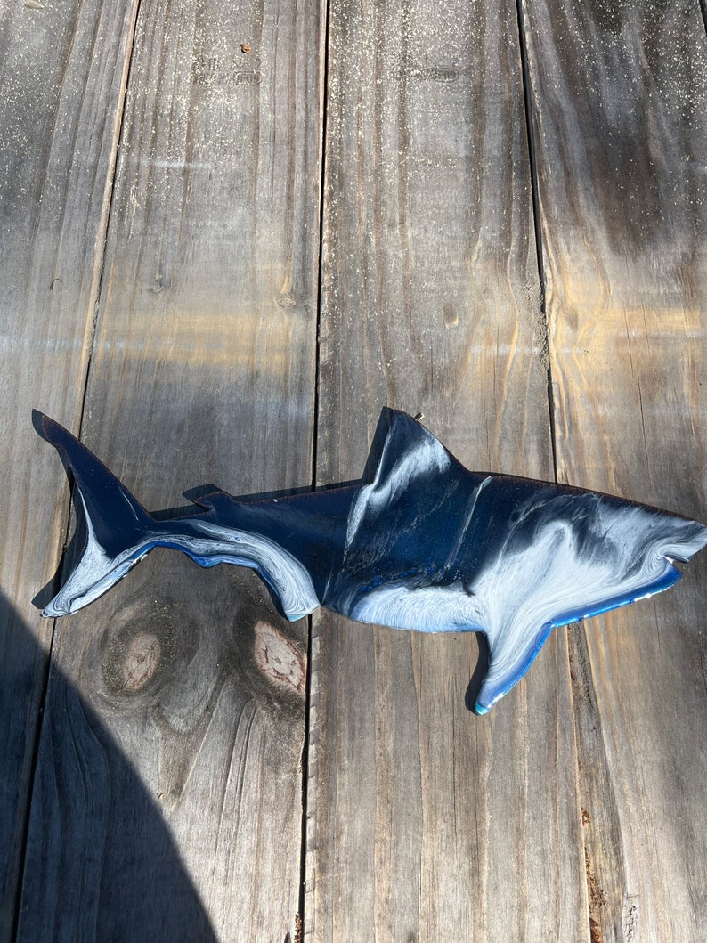 May include: A black and white shark wall decor with blue accents. The shark is made of metal and has a marbled finish.