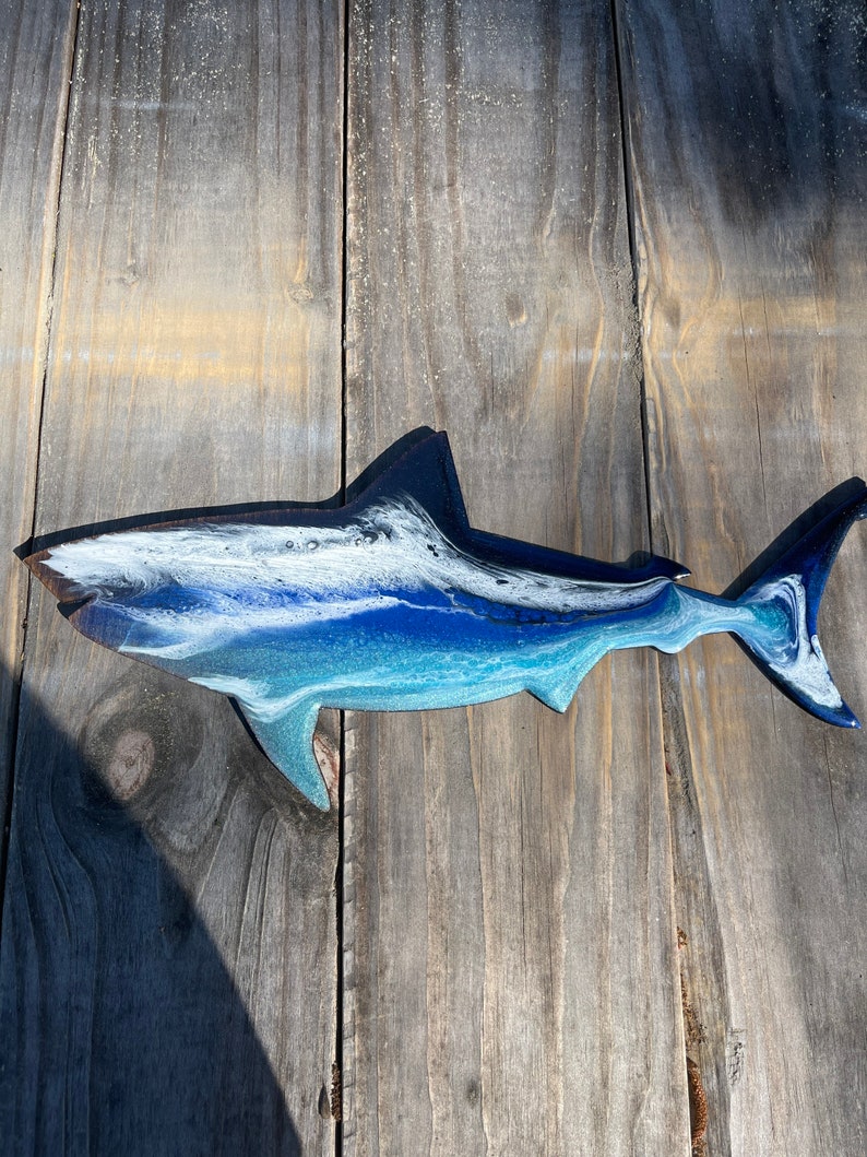 May include: A blue, white, and black resin shark wall decor. The shark is painted with a swirling, abstract design.