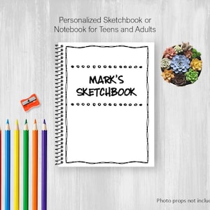 May include: A white spiral-bound sketchbook with the text "MARK'S SKETCHBOOK" in black. The image includes a set of colorful pencils, a pencil sharpener, and a small succulent arrangement. The text "Personalized Sketchbook or Notebook for Teens and Adults" is also visible.