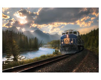 May include: A scenic landscape featuring a blue and white train traveling along a track beside a river. The train has the number 8013 on the front. The sky is filled with clouds and the sun is shining through.