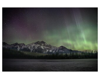 May include: A night sky with a vibrant green and purple aurora borealis over a snow-capped mountain range. The mountains are silhouetted against the starry sky.