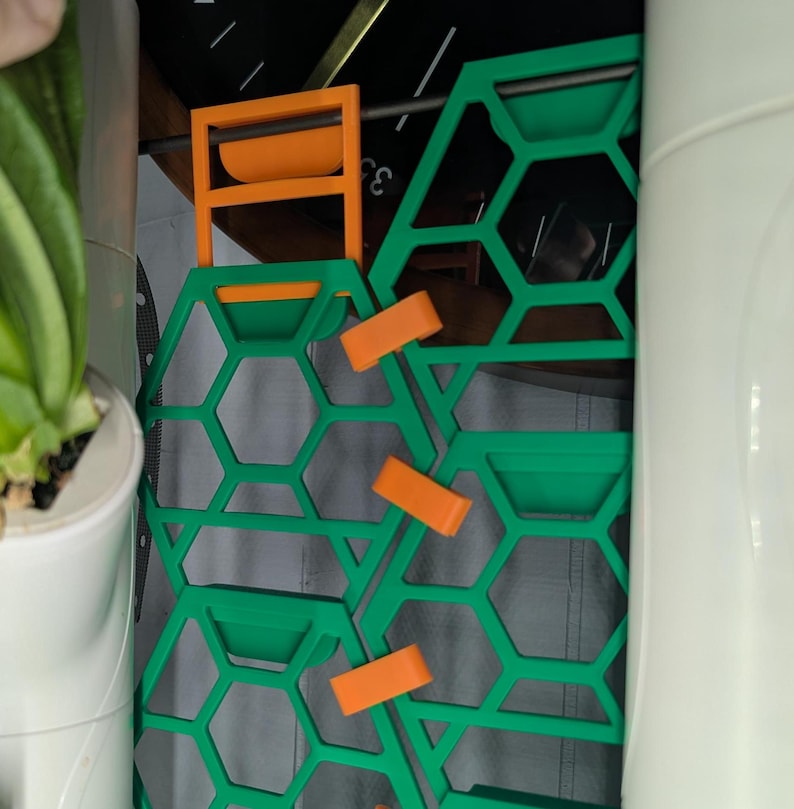 May include: A set of three green honeycomb-shaped panels with orange clips. The panels are designed to be connected together to create a larger structure.