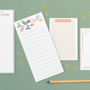 May include: Four different notepad designs with lined paper. The notepads have various designs including a heart with the text "Teach, Love, Inspire", a design with colorful paper clips, a design with a floral pattern, and a design with a gray line and the letter "G". A pencil is also included.