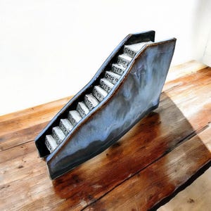 May include: A ceramic sculpture of a staircase with the word "STEP" written on each step. The sculpture is painted in shades of blue and brown and has a textured surface.