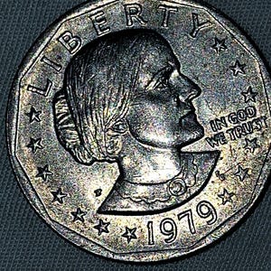 Może przedstawiać: Srebrna amerykańska moneta o wartości ćwierć dolara z wizerunkiem profilu kobiety na awersie. Na monecie widnieją napisy "LIBERTY" i "IN GOD WE TRUST". Widoczny jest również rok wybicia "1979".