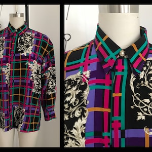 Könnte beinhalten: Ein langärmliges Hemd mit Knöpfen, schwarzem Hintergrund und einem bunten Karomuster. Das Hemd hat ein goldenes Blumenmuster und einen goldenen Knopf.