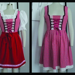 Peut inclure: Une robe de dirndl en vichy rouge et blanc avec une bordure en dentelle blanche et un n&oelig;ud en ruban rouge. La robe est accompagn&eacute;e d'un chemisier blanc &agrave; manches bouffantes et d'un col en dentelle blanche.