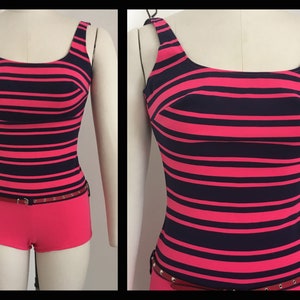 May include: A pink and navy blue striped swimsuit with a red belt and silver studs. The swimsuit has a scoop neck and a built-in bra.