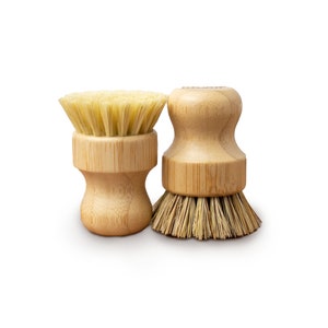 May include: Two wooden dish brushes with natural bristles. The brushes have a round, wooden handle with a textured surface.