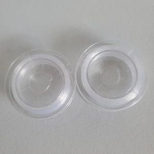 May include: Two clear plastic spools of white thread.