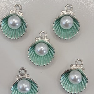 May include: Five silver and green seashell charms with a white pearl in each. The charms are perfect for jewelry making or adding a touch of whimsy to crafts.