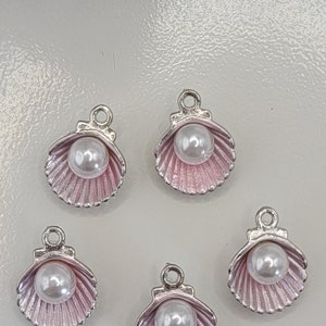 May include: Five silver charms shaped like seashells with a pink interior and a white pearl in the center.