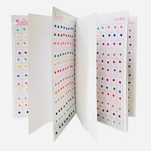 May include: A book with pages filled with small, colourful dots. The book is open to show different colour options. The book is titled "Swastik" and "bindles".