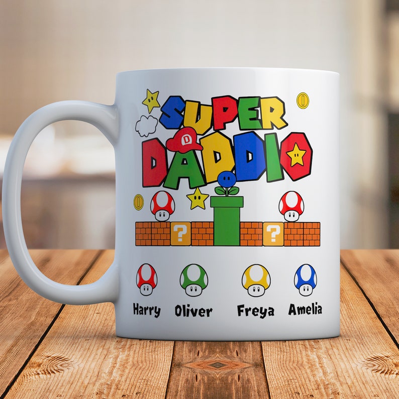 May include: White ceramic mug with a colorful Super Daddi design featuring a mushroom, a pipe, and stars. The mug has four mushroom characters with the names Harry, Oliver, Freya, and Amelia.