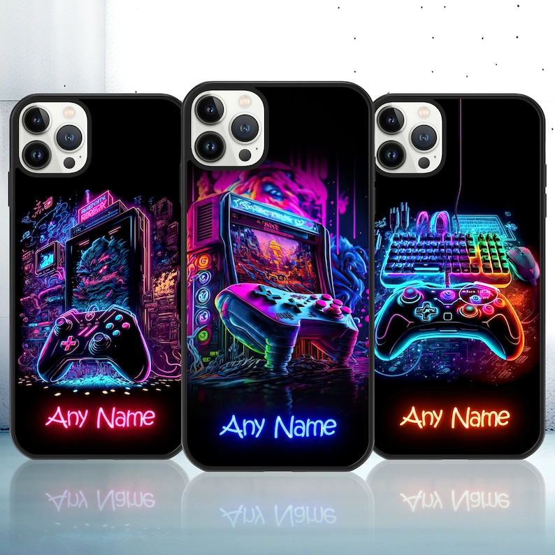 Op de afbeelding: Drie zwarte telefoonhoesjes met neonkleurige ontwerpen. De ontwerpen bevatten een retro-videogamesysteem, een joystick en een toetsenbord. De tekst "Any Name" staat op elk hoesje.