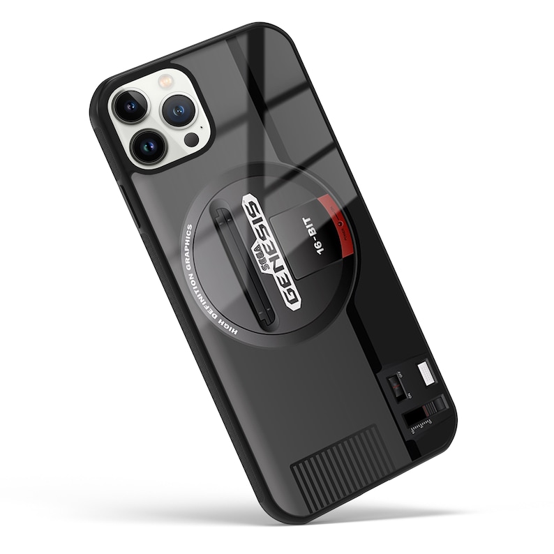 May include: Black phone case with a Sega Genesis design. The case features the iconic Sega Genesis logo, the words "16-BIT" and "HIGH DEFINITION GRAPHICS", and a slot for a game cartridge.