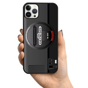 May include: Black phone case with a Sega Genesis 16-bit video game console design. The case has a black and red color scheme and features the Sega Genesis logo and the words "High Definition Graphics".