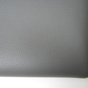 May include: Close-up of a section of gray leather material. The leather has a textured surface with a subtle grain pattern. The edges of the material are visible, showing a clean, finished look. The background is white.