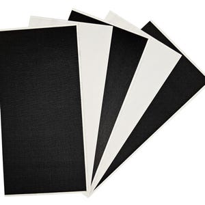 Op de afbeelding: Vijf vellen stof, twee zwart en drie wit, in een waaier gerangschikt. De stof heeft een textuur en een geweven uiterlijk.