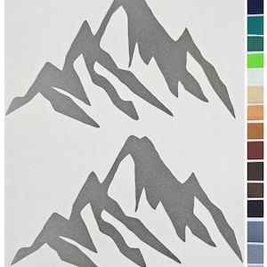 Puede incluir: Dos calcomanías de montañas grises sobre un fondo blanco. El diseño de la cordillera es una silueta con picos y laderas irregulares. Un cuadro de colores con varias muestras de tela es visible en el lado derecho de la imagen.