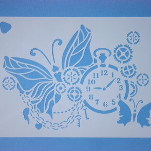 May include: White stencil with a butterfly design, clock face with Roman numerals, and gears. The butterfly has a chain of hearts attached to it.