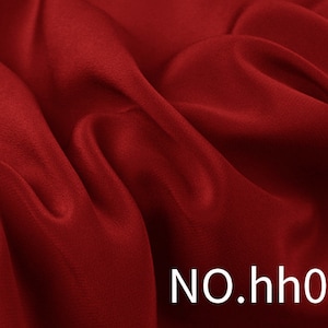 Può includere: Primo piano di un tessuto rosso scuro con morbide pieghe e una superficie strutturata. Il tessuto ha un aspetto lussuoso, con la luce che si riflette sulle curve. Il testo "NO.hh01" è visibile nell'angolo in basso a destra.
