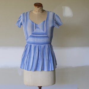 May include: A blue and white striped cotton blouse with a gathered waist and short sleeves.