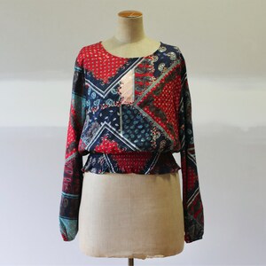 Puede incluir: Una blusa de manga larga con estampado rojo, azul y verde y cintura elástica fruncida.