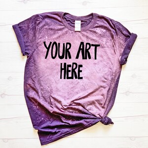 Puede incluir: Una camiseta de color morado con efecto tie-dye con el texto "YOUR ART HERE" en letras negras.