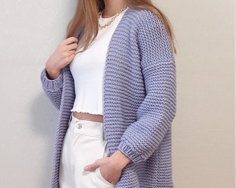 May include: A light purple knitted cardigan with a long, relaxed fit. The cardigan has a simple design with a V-neck and long sleeves.