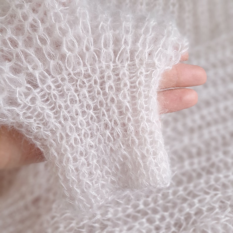 May include: White fuzzy knit fabric with a loose, open weave. The fabric is soft and delicate, with a slightly textured surface.