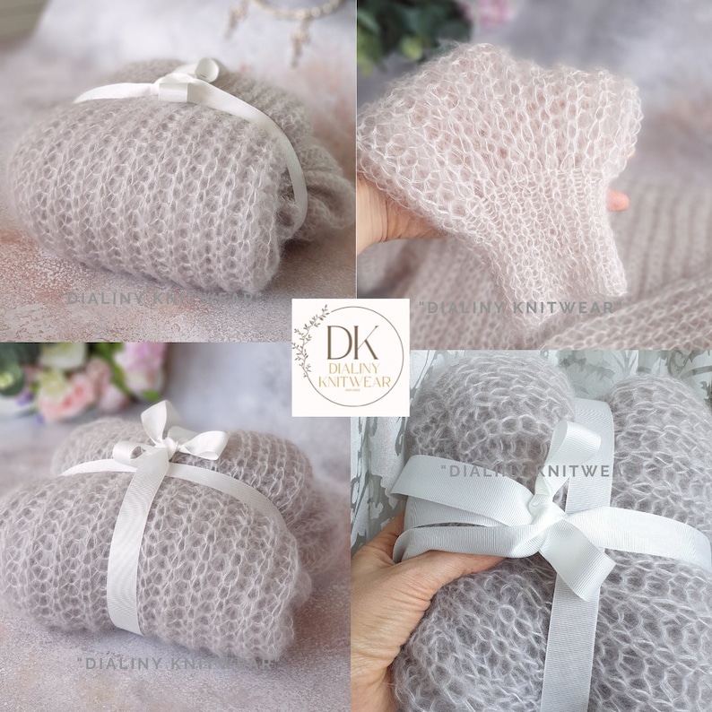 May include: A light gray knitted baby blanket with a white satin ribbon tied around it. The blanket is made of a soft, delicate yarn and has a delicate, lacy texture. The blanket is folded in half and tied with a white ribbon. The blanket is perfect for a newborn baby.