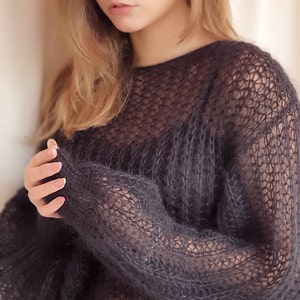 May include: A black, sheer, knitted sweater with a loose fit and long sleeves.