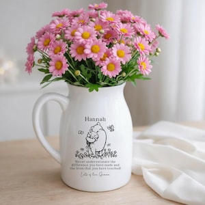 May include: A white ceramic jug filled with a large bouquet of pink daisies. The jug features a black line drawing of Winnie the Pooh holding Piglet, the name Hannah, and the text: Never underestimate the difference you have made and the lives that you have touched! Lots of love Gemma.